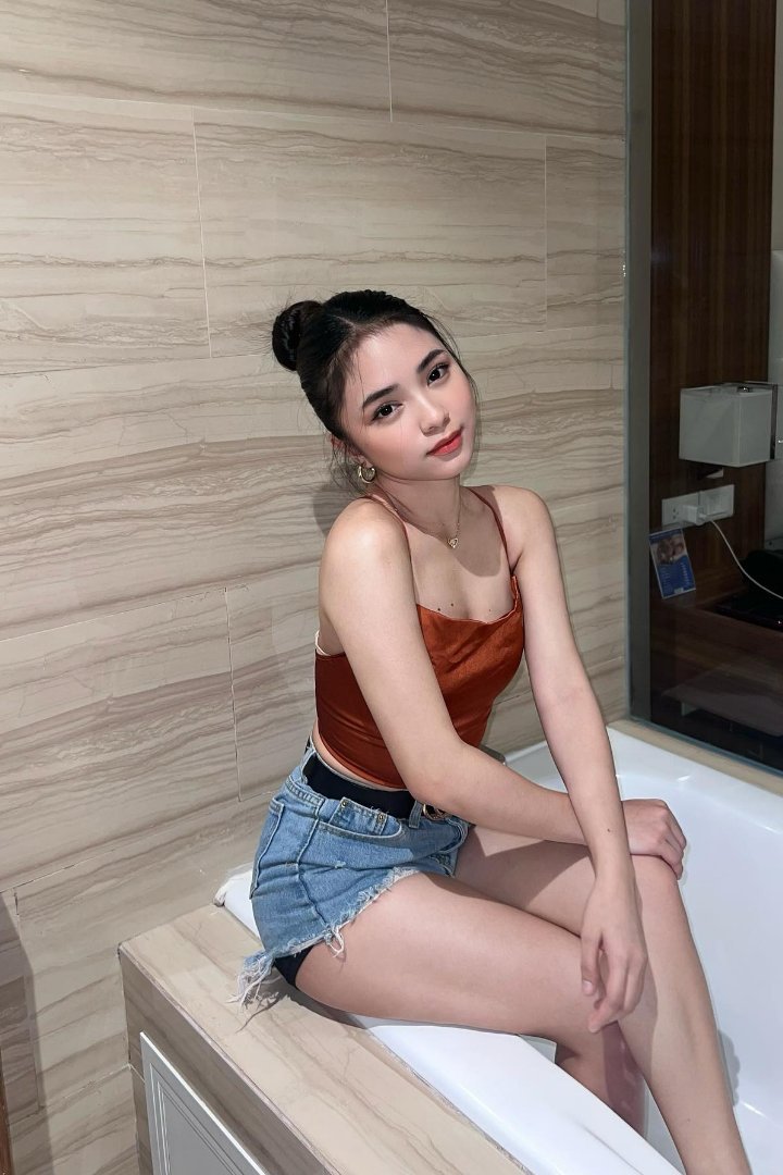 KL Escort Girl Young woman in denim shorts and top sitting on the edge of a bathtub. Sex Service Malaysia