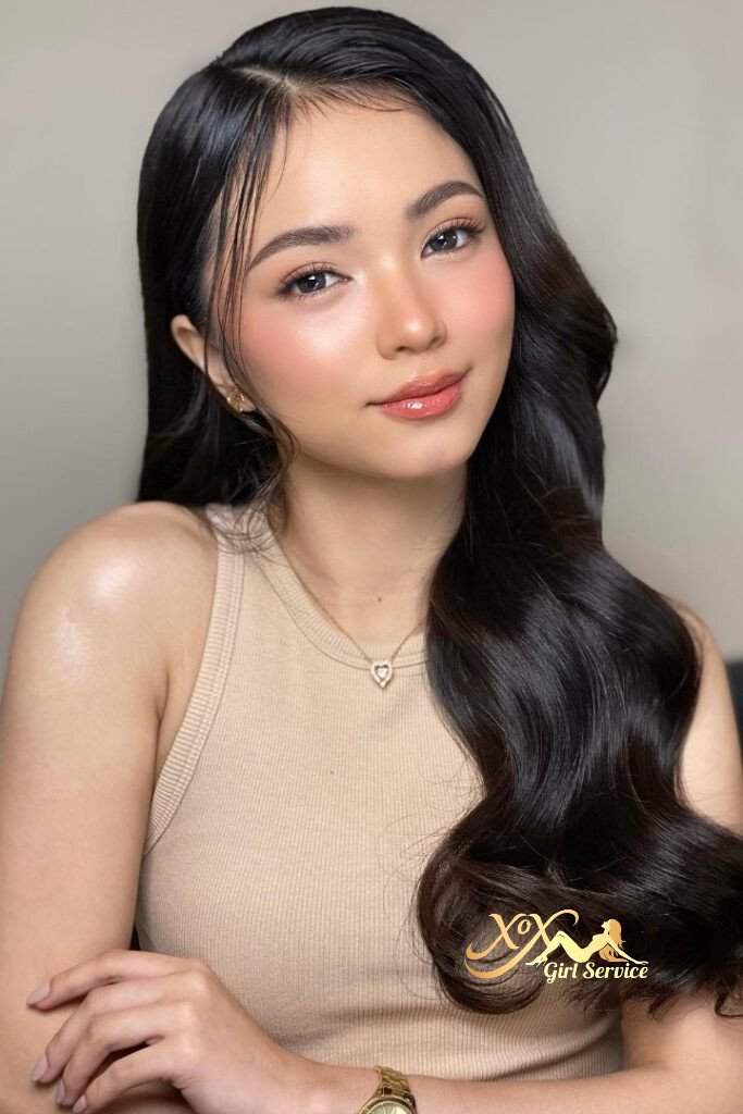 Beautiful Asian woman with long dark hair and a beige top smiling softly.