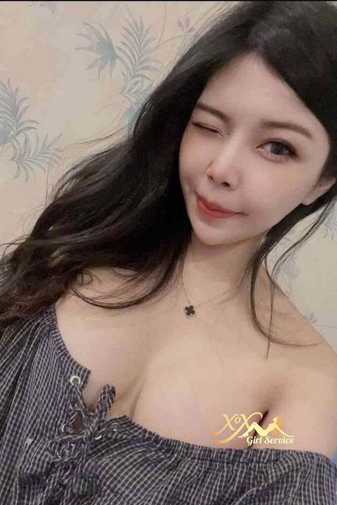 Attractive Asian woman winking, wearing a necklace and off-the-shoulder top. Chinese KL Escort.