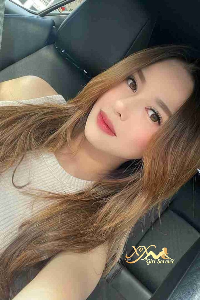 Beautiful Malay woman with long brown hair, light makeup, inside a car.