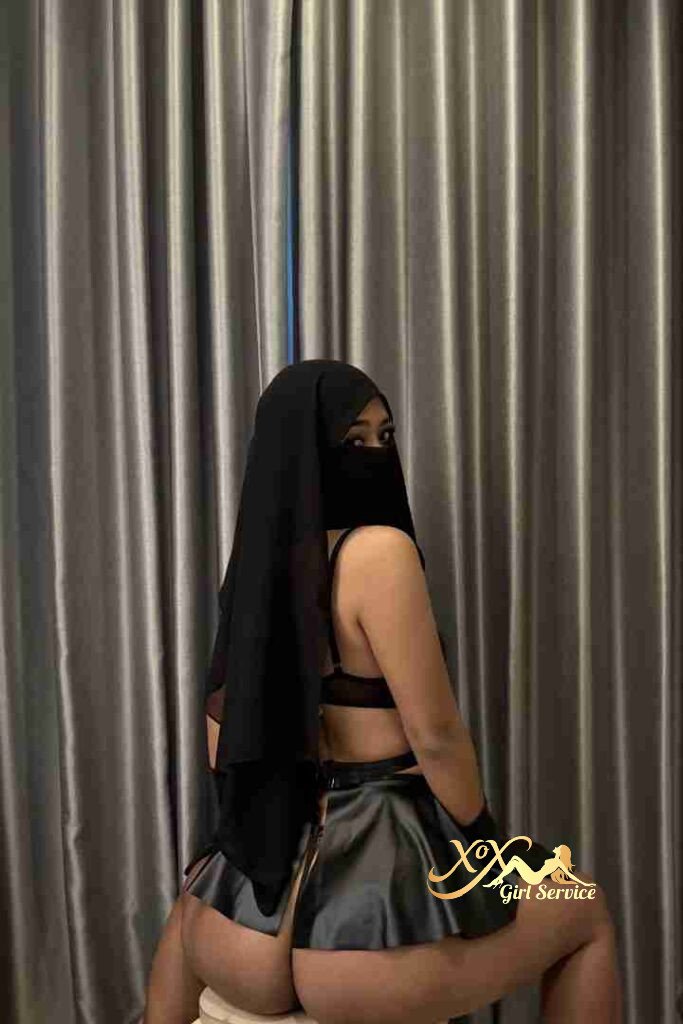 Malay woman in hijab and lingerie, posing against a curtain backdrop.
