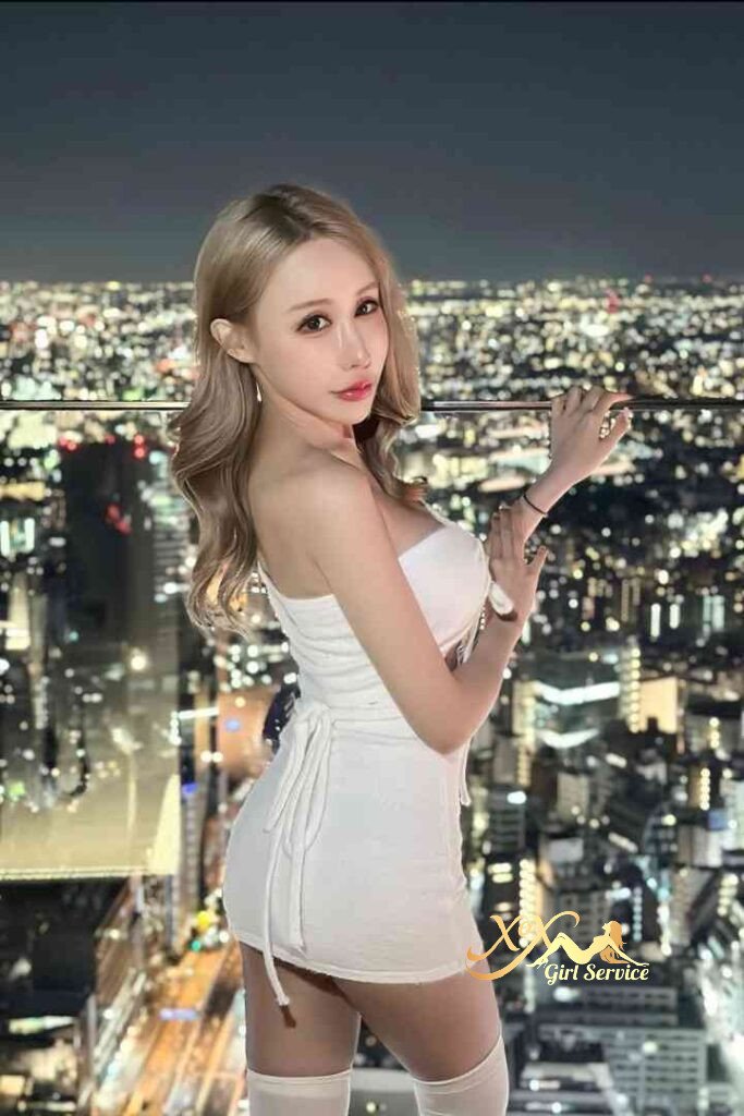 Sexy Vietnamese woman in white dress on rooftop with city lights. KL Escort.