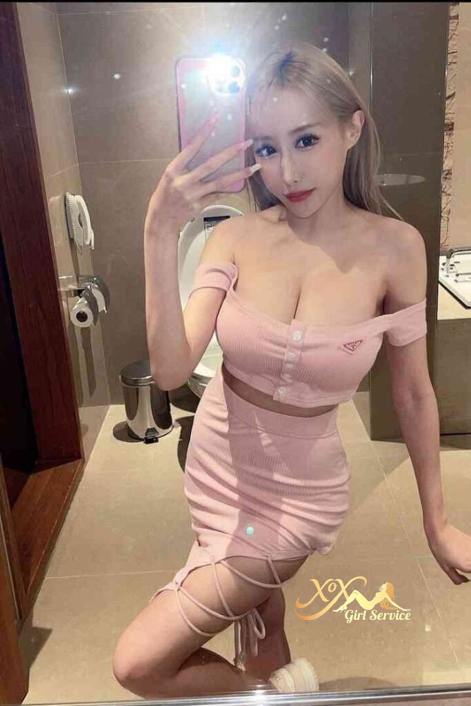 Sexy woman in pink outfit taking selfie in bathroom. KL Escort.