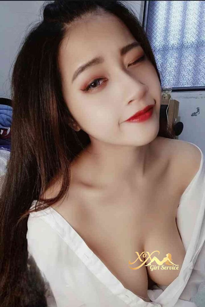 Stunning Vietnamese woman with red lipstick and a white shirt, winking playfully at the camera.