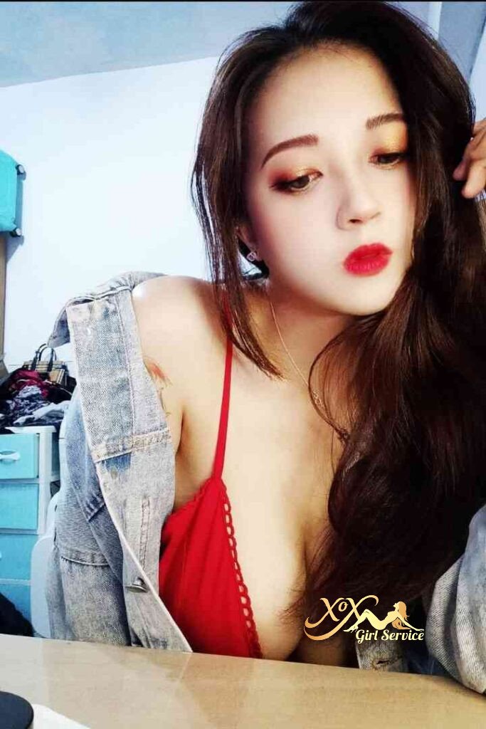 Sexy Vietnamese woman in red top and denim jacket, looking down. KL Escort.