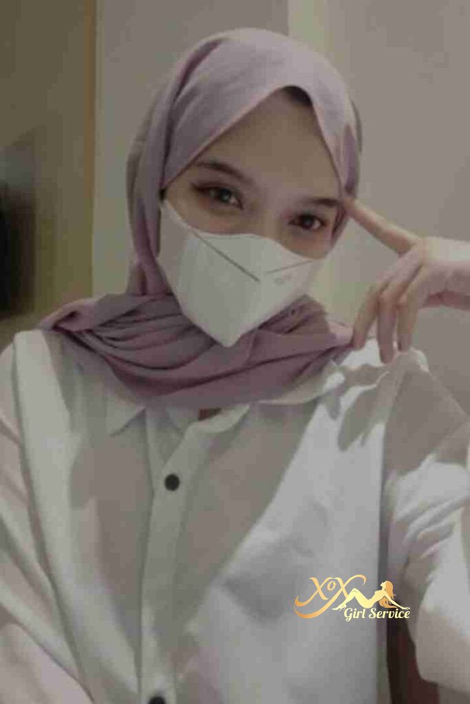 Woman in hijab and mask, light purple headscarf, white shirt.